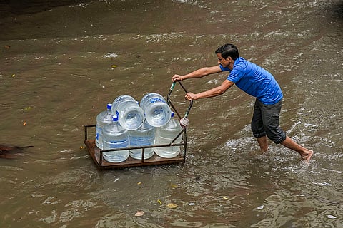 Delhi Weather: A man pushes a loaded cart through a waterlogged road 